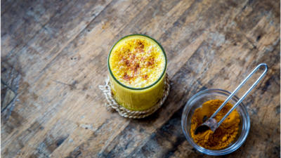a cup of a yellow drink with brown substance sprinkled on top